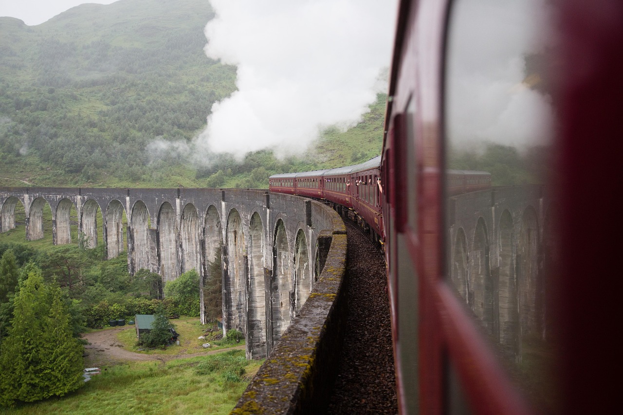 Treno in partenza dalla stazione di Hogsmeade, con paesaggi incantevoli sullo sfondo.