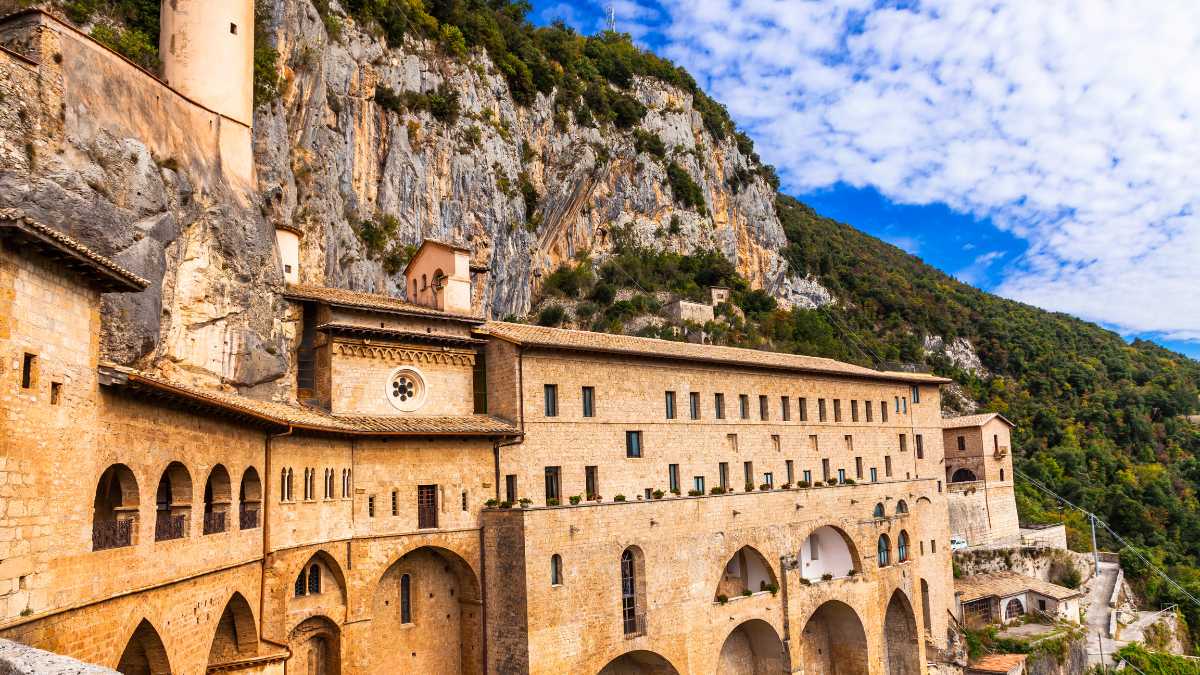 Monastero immerso tra le montagne, avvolto da nebbia e vegetazione, simbolo di spiritualità e mistero.
