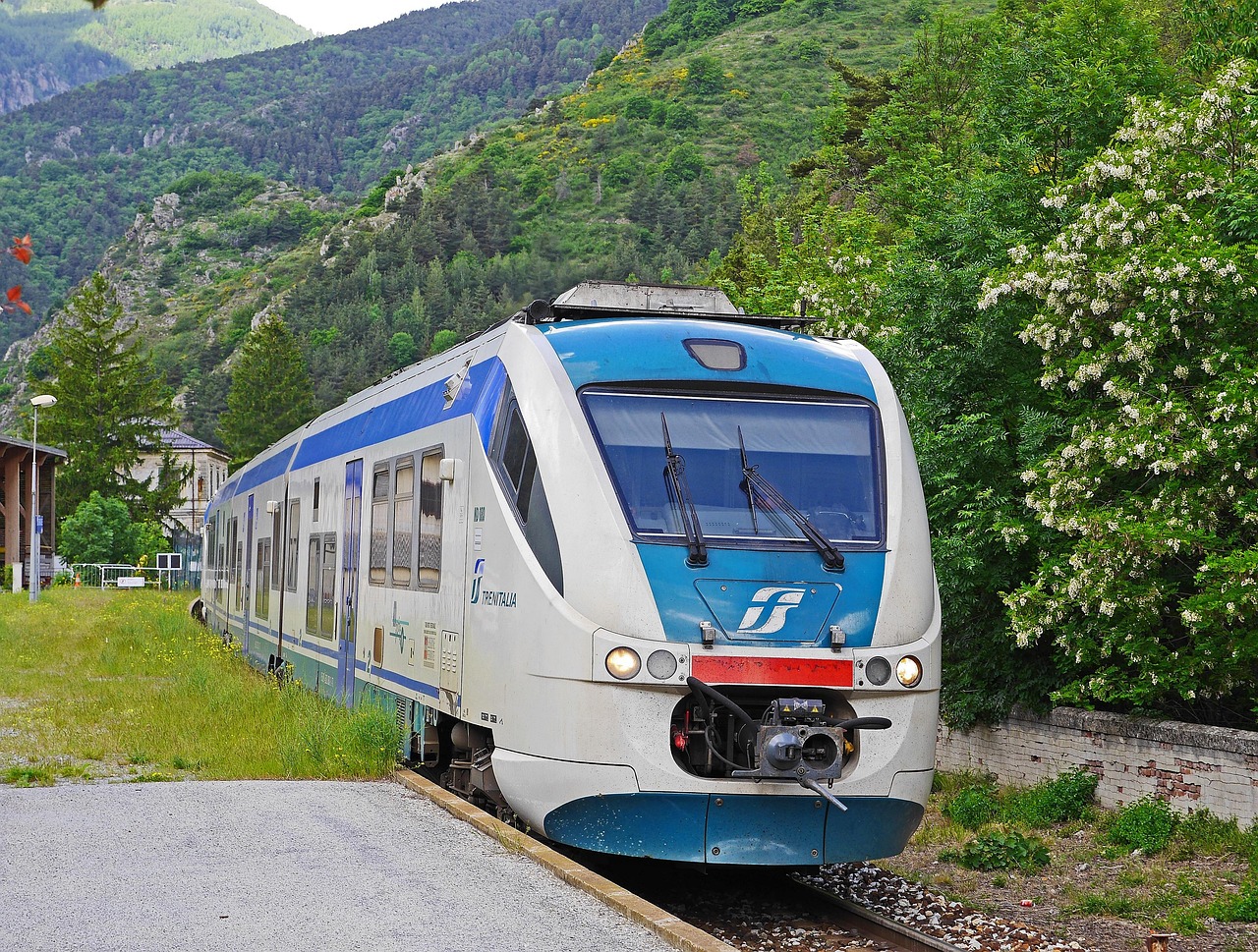 Treno che attraversa un paesaggio panoramico italiano, con colline e vigneti sullo sfondo.