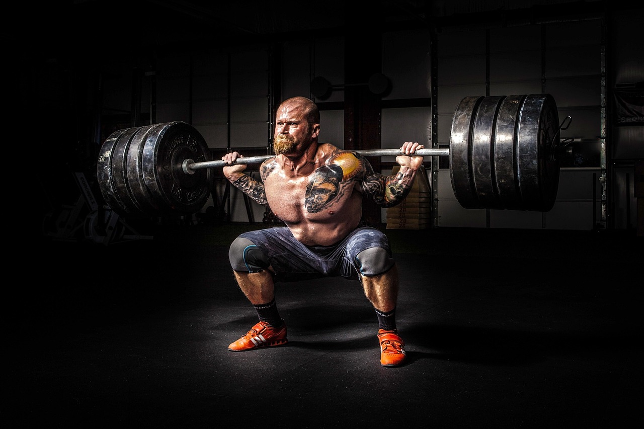 Uomo over 40 che esegue un esercizio di sollevamento pesi, allenamento 5x5 in palestra.