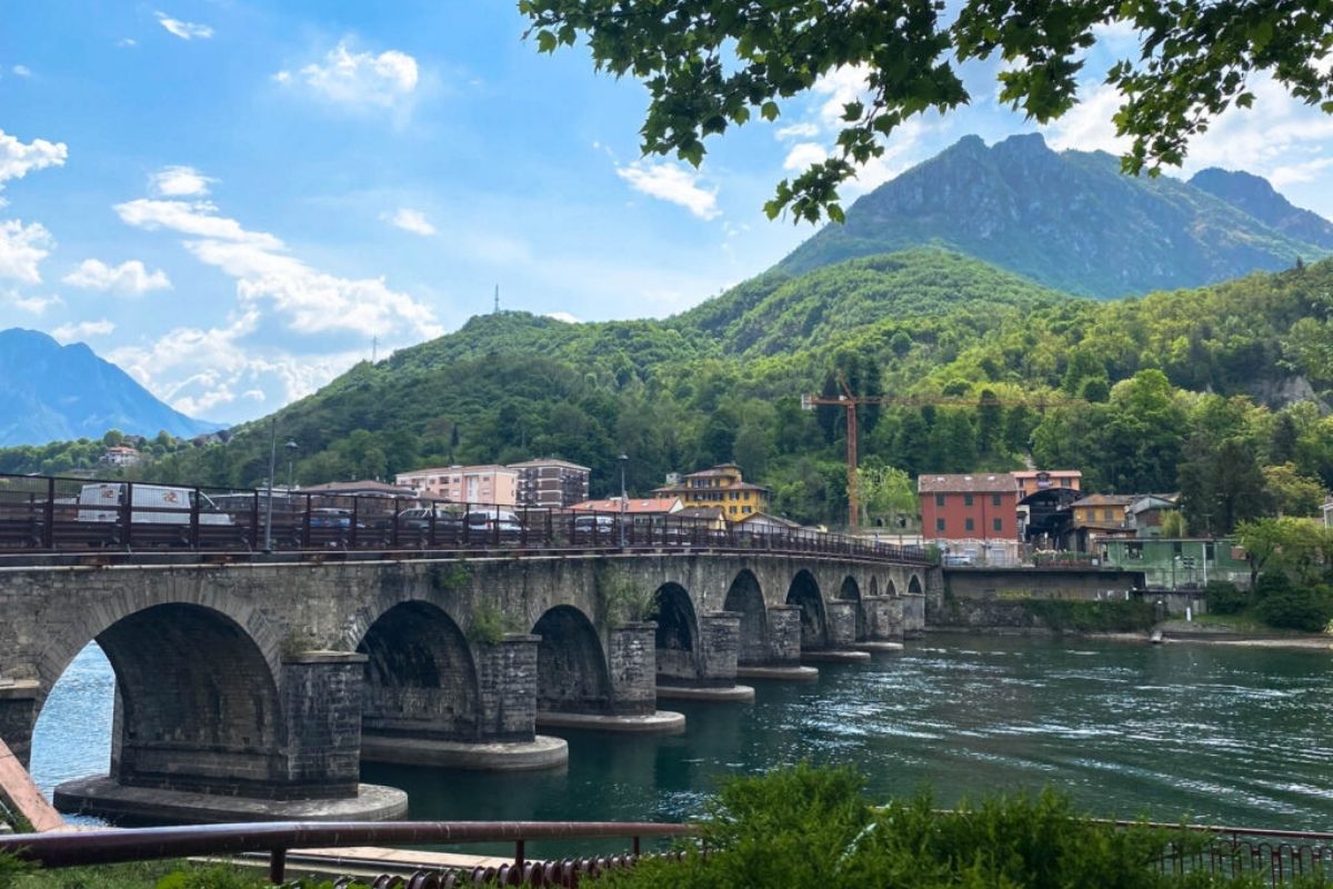 Vista di una cattedrale naturale con alberi e un ponte sospeso, evocando atmosfere tolkeniane in Lombardia.